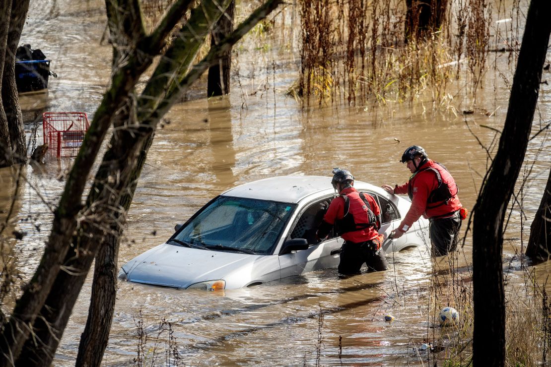 Such- und Rettungskräfte untersuchen ein von Überschwemmungen umgebenes Auto in San Jose, Kalifornien.