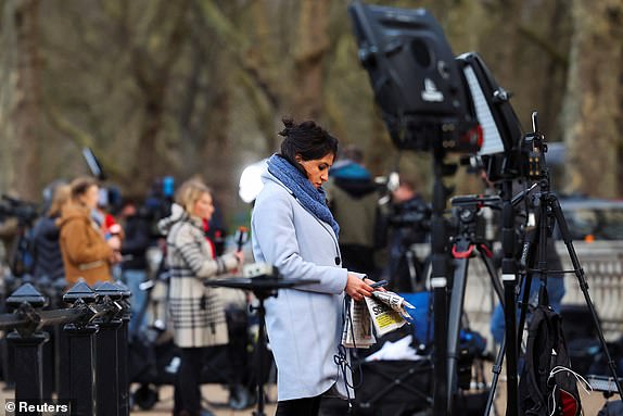 A member of the media holds a phone and newspaper while working outside Buckingham Palace, after it was announced that Britain's King Charles has been diagnosed with cancer, in London, Britain, February 6, 2024. REUTERS/Toby Melville