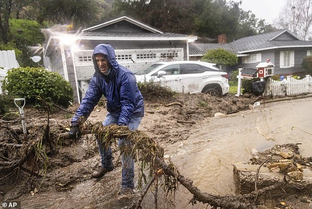 Jeffrey Raines clears debris from a mudslide at his parents' home during a rainstorm in Los Angeles on Monday