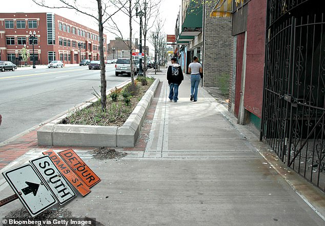 Ein umgestürztes Schild steht auf dem Bürgersteig, als ein Paar am Donnerstag, den 20. April 2006, den Broadway in Gary, Indiana entlang geht