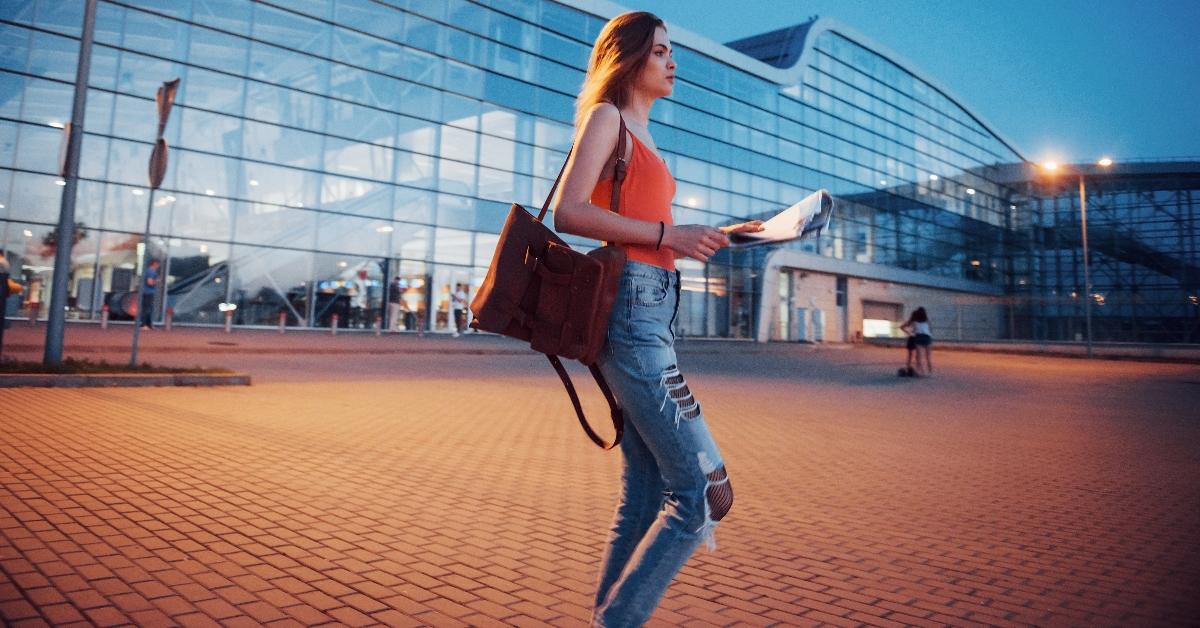 Junge Frau reist nachts in der Nähe des Terminals des Flughafens oder Bahnhofs, liest einen Stadtplan und sucht nach einem Hotel – Stockfoto