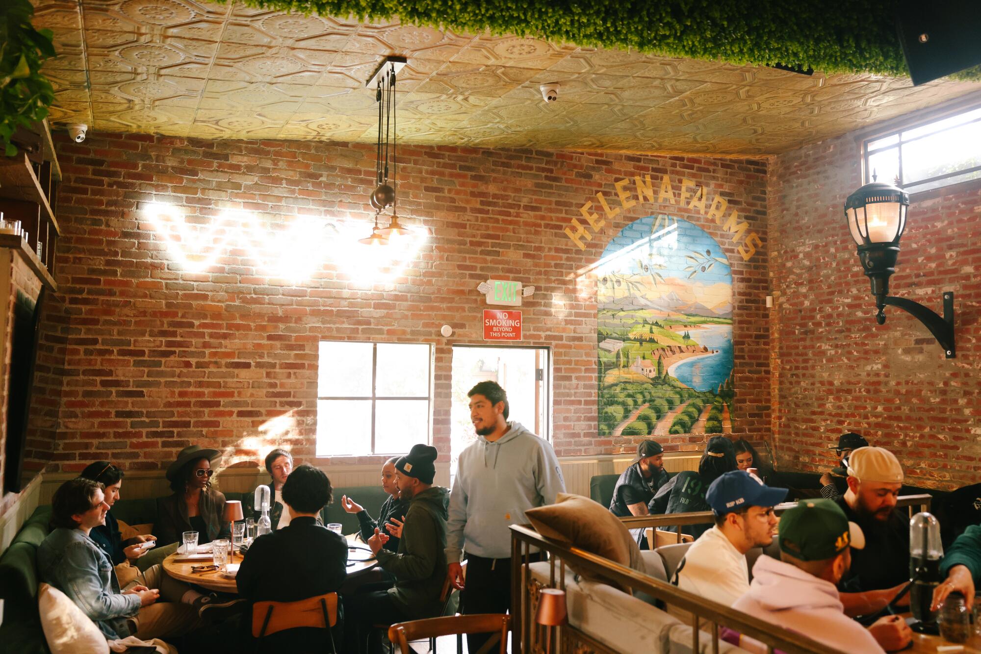 Menschen sitzen in einem Restaurant-ähnlichen Raum mit Backsteinwänden und Cannabis-Markenkunst.