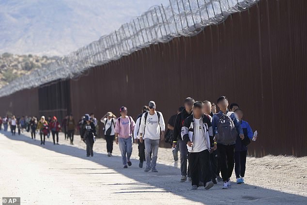 Eine Gruppe von Menschen, darunter viele aus China, geht am Dienstag, 24. Oktober 2023, in der Nähe von Jacumba, Kalifornien, an der Mauer entlang, nachdem sie die Grenze zu Mexiko überquert hat, um Asyl zu beantragen.  (Den abgebildeten Migranten werden keine Verbindungen zur KPCh vorgeworfen)
