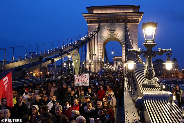 Menschen gehen über die Kettenbrücke, während sie an einem Protest teilnehmen, der den Rücktritt der ungarischen Präsidentin Katalin Nova fordert