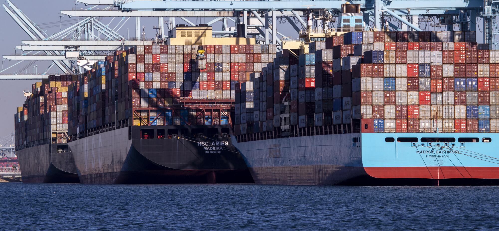 Drei Containerschiffe liegen an einem Hafen.