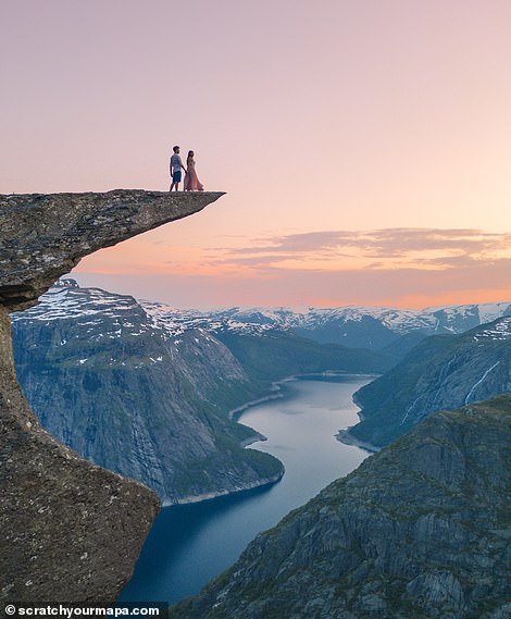 Das Paar steht auf Trolltunga.  Sie ist eine der erstaunlichsten Felsformationen Norwegens und „schwebt“ 700 Meter (2.296 Fuß) über dem Ringedalsvatnet-See
