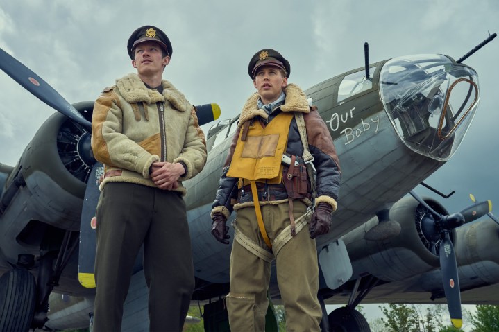 Callum Turner und Austin Butler stehen in Masters of the Air in der Nähe eines Flugzeugs.