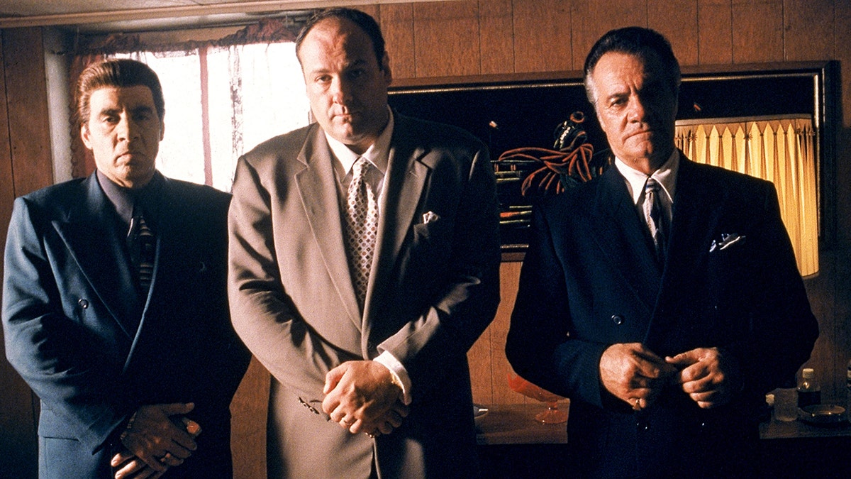 James Gandolfini steht in der Mitte zwischen zwei Männern, die vor der Kamera Gangster spielen