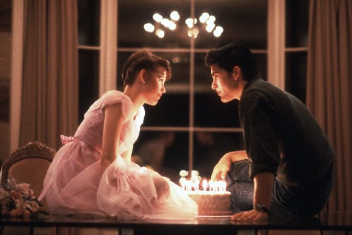 Molly Ringwald und Michael Schoeffling sitzen an einem Tisch und beugen sich über eine Geburtstagstorte.