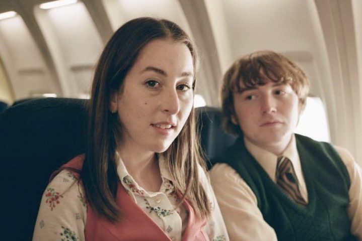 Ein Mädchen und ein Junge sitzen nebeneinander im Flugzeug.