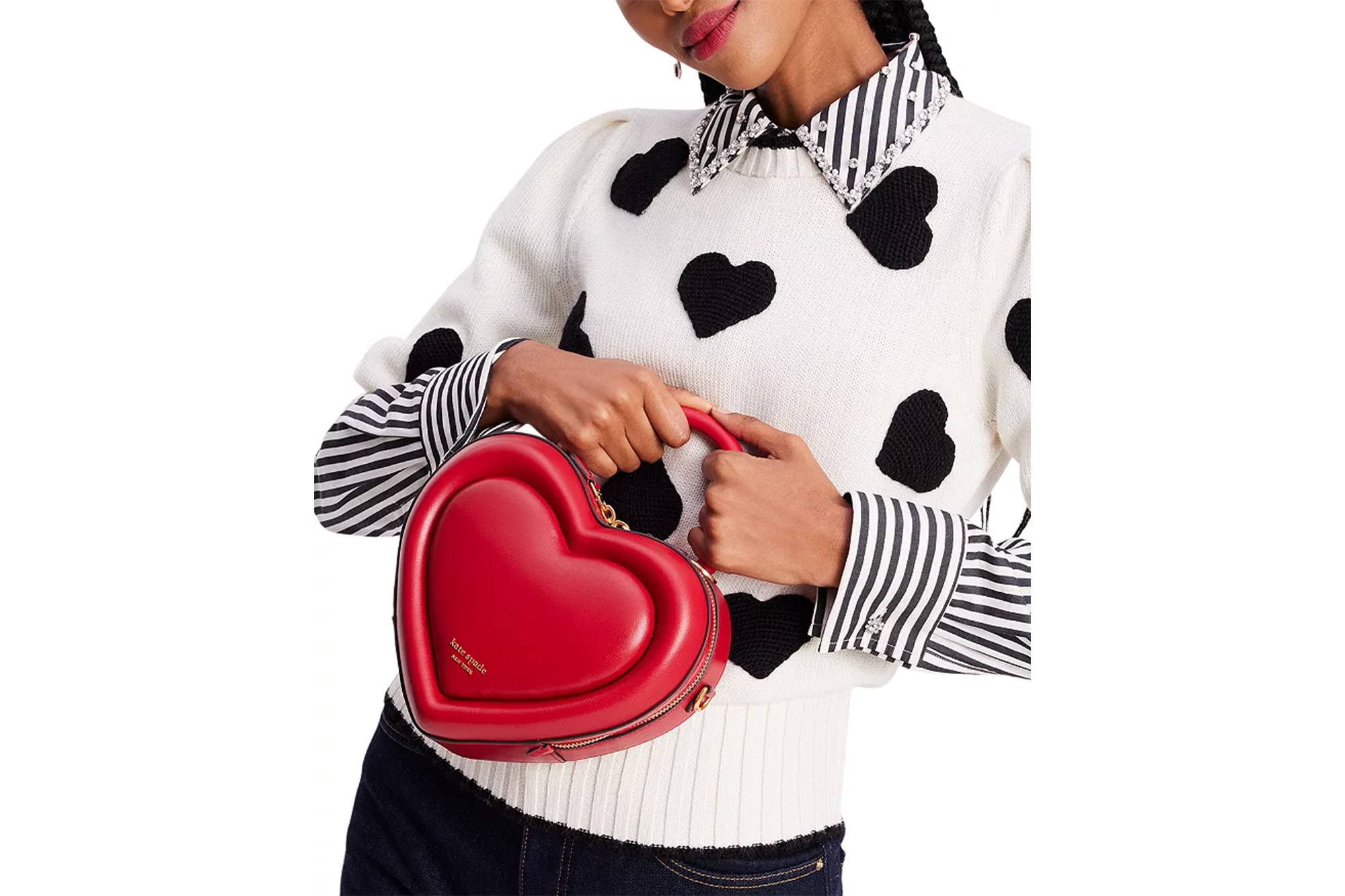 Ein Model in einem Herzpullover mit einer roten Handtasche