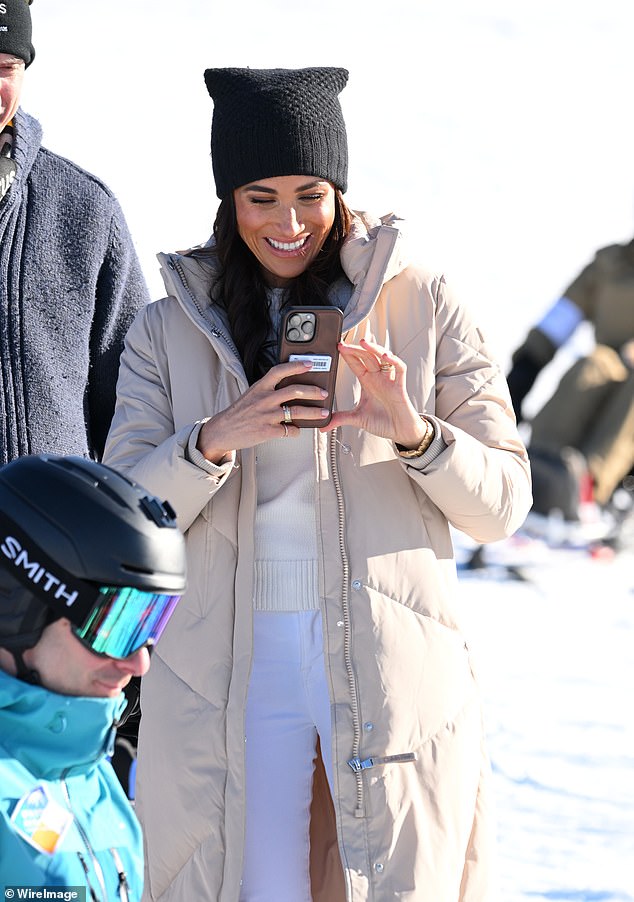 Meghan lacht, als sie gestern beim Skifahren auf den Pisten scheinbar Inhalte auf ihrem Handy sammelt
