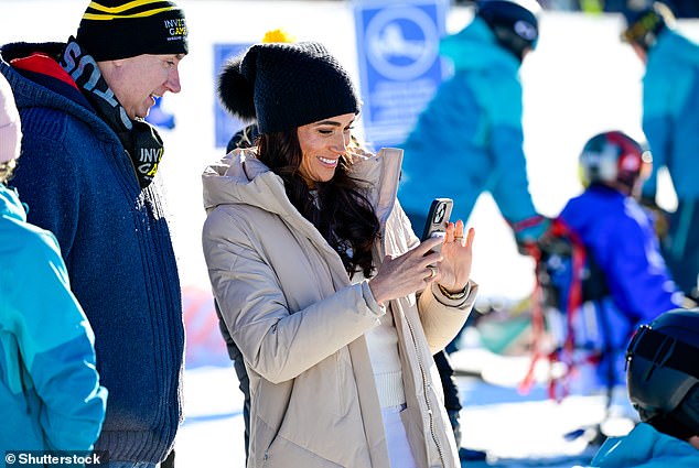 Meghan appeared to be filming or taking pictures watched by an Invictus official on the slopes yesterday