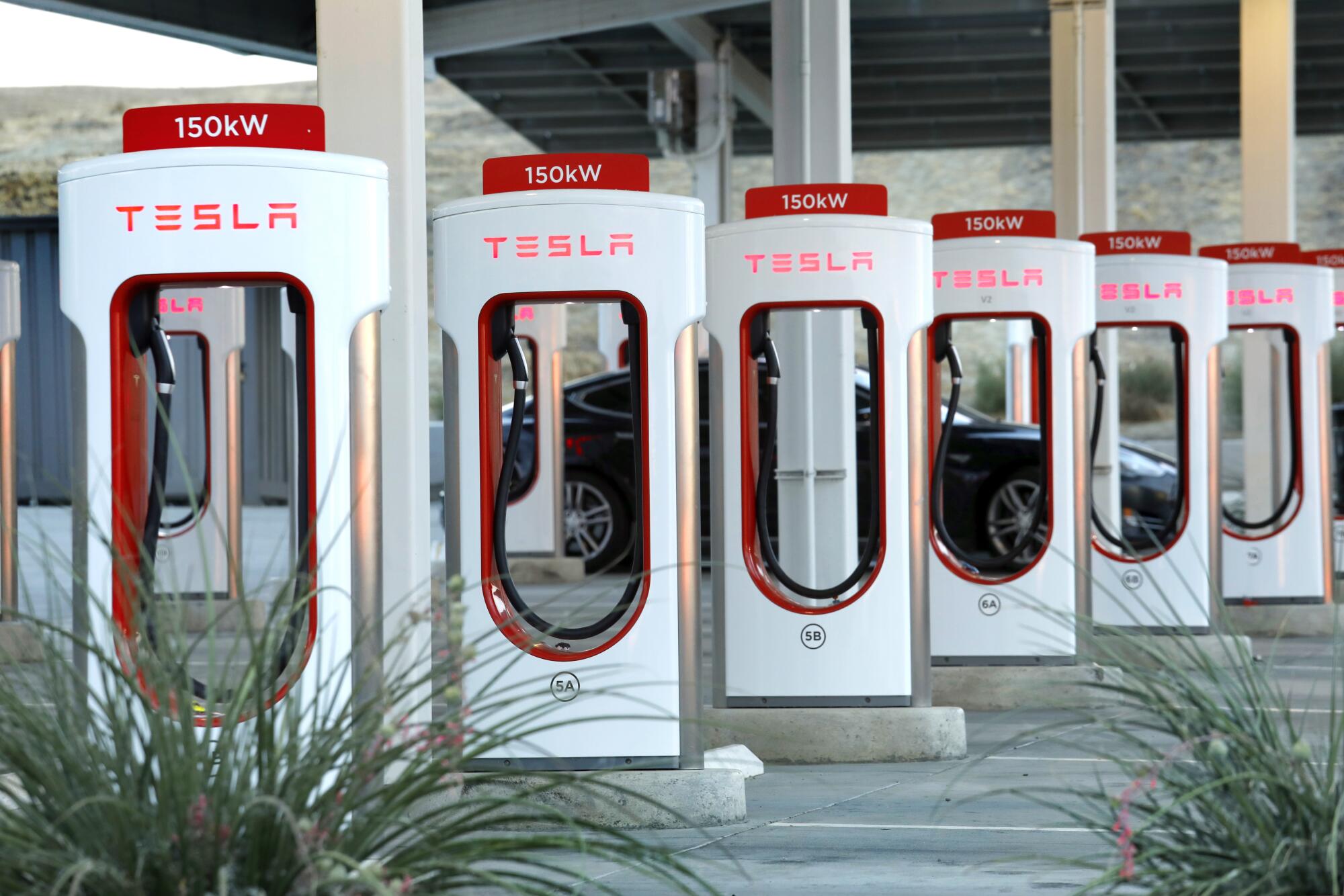 Eine Reihe rot-weißer Tesla-Fahrzeugladegeräte.