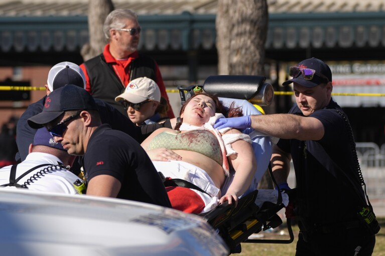 Eine Person wird nach einer Schießerei bei der NFL-Football-Super-Bowl-Feier der Kansas City Chiefs am Mittwoch, 14. Februar 2024, in Kansas City, Missouri, zu einem Krankenwagen gebracht. Mehrere Menschen seien verletzt worden, sagte ein Feuerwehrmann.  (AP Photo/Charlie Riedel)