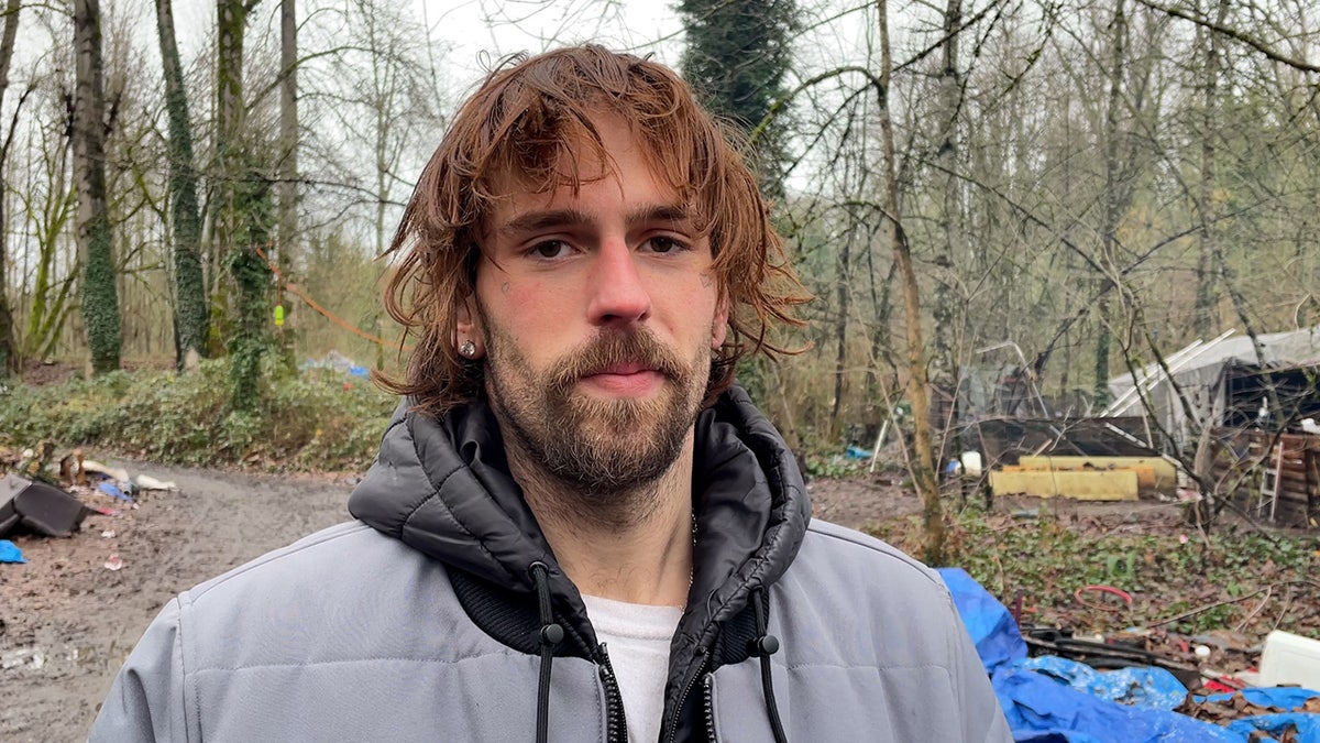 Mann in grauer Jacke steht im Obdachlosenlager
