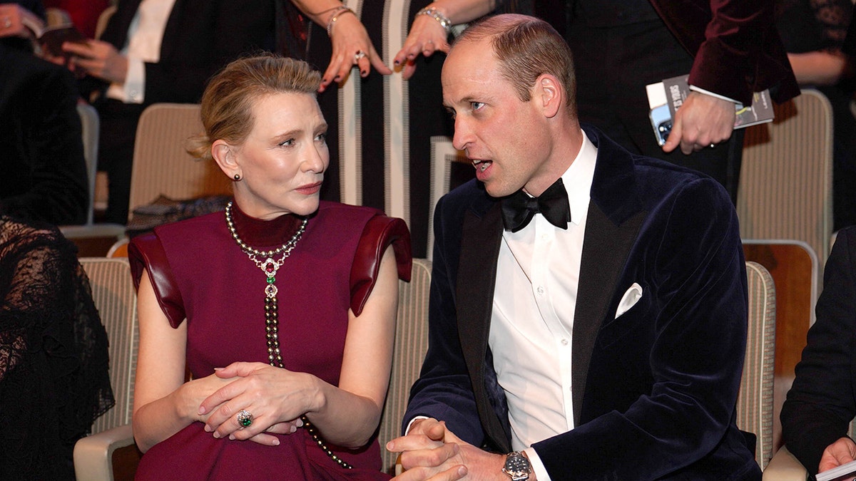 Prinz William sitzt neben Cate Blanchett in einem roten Kleid mit Flügelärmeln bei den BAFTAS
