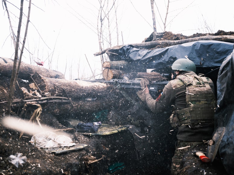 Ein ukrainischer Scharfschütze, der in einem Schützengraben positioniert ist, zielt mit einem Gewehr.