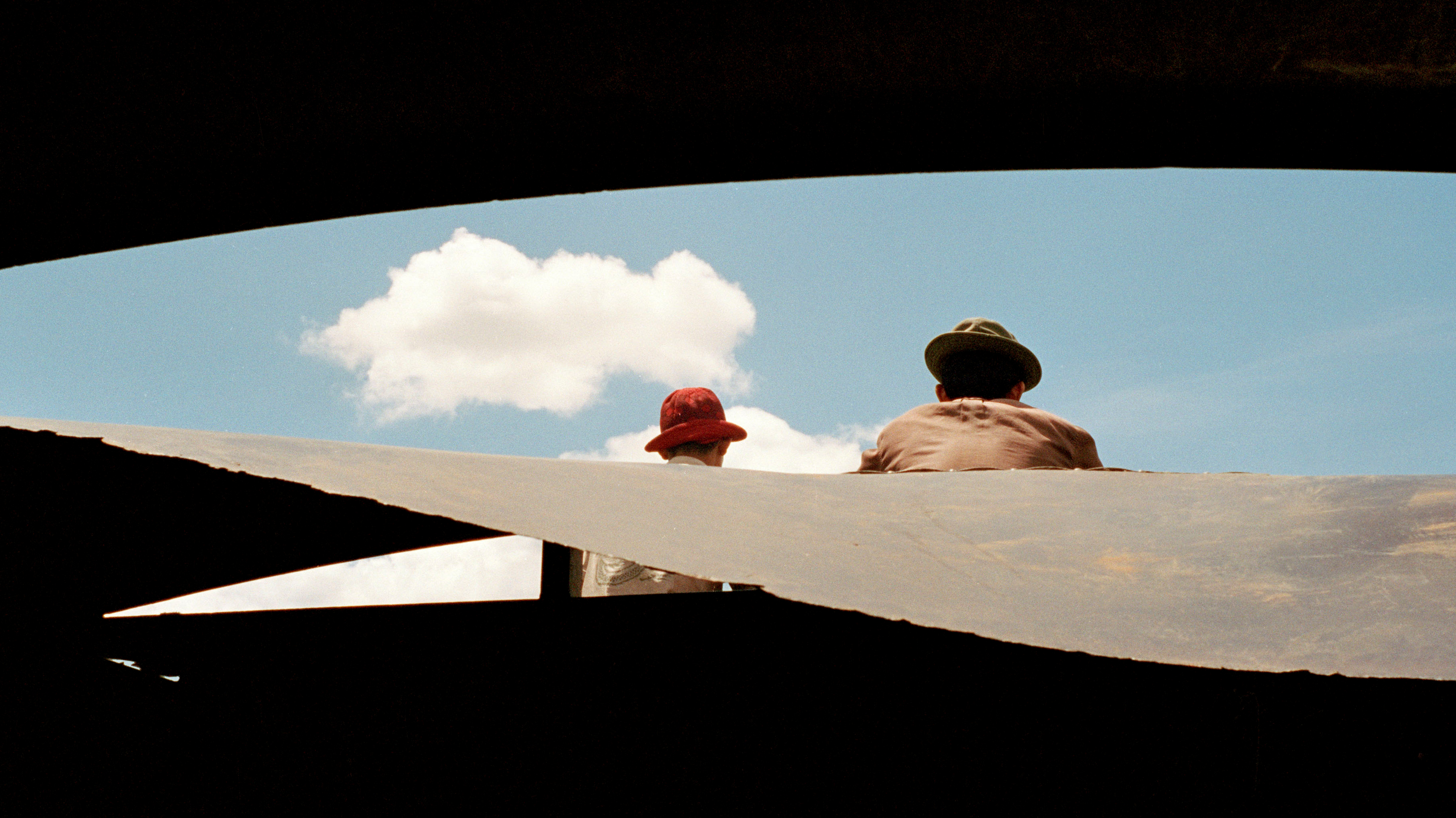 Zwei Männer mit Hüten blicken in einen wolkenverhangenen blauen Himmel