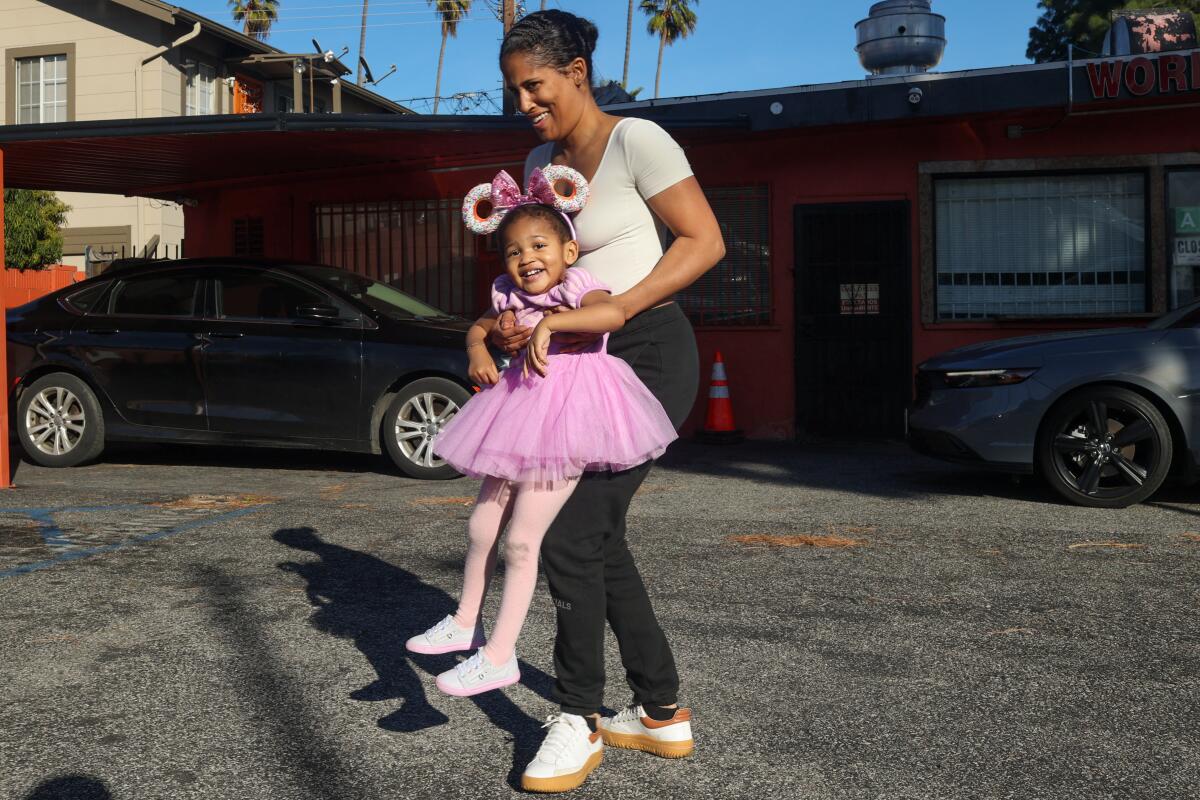 Porsha Scott wiegt ihre Tochter Amil Flowers, 2, während sie auf dem Parkplatz auf ihre Bestellung warten.