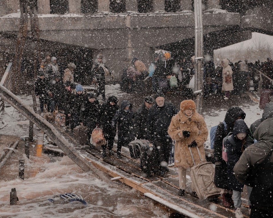 Schnee fällt auf Menschen, die versuchen, die Trümmer einer zerbombten Brücke zu überqueren