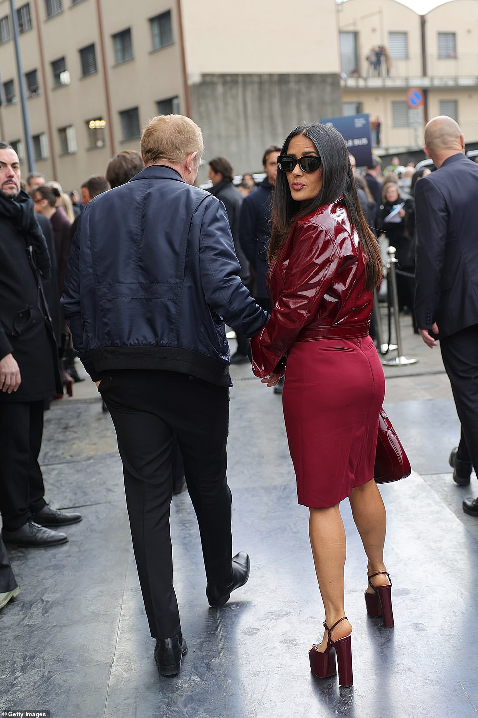 Salma, 57, looked stylish as she opted for a PVC burgundy jacket with black cuffs and a matching red skirt as she pouted at the camera