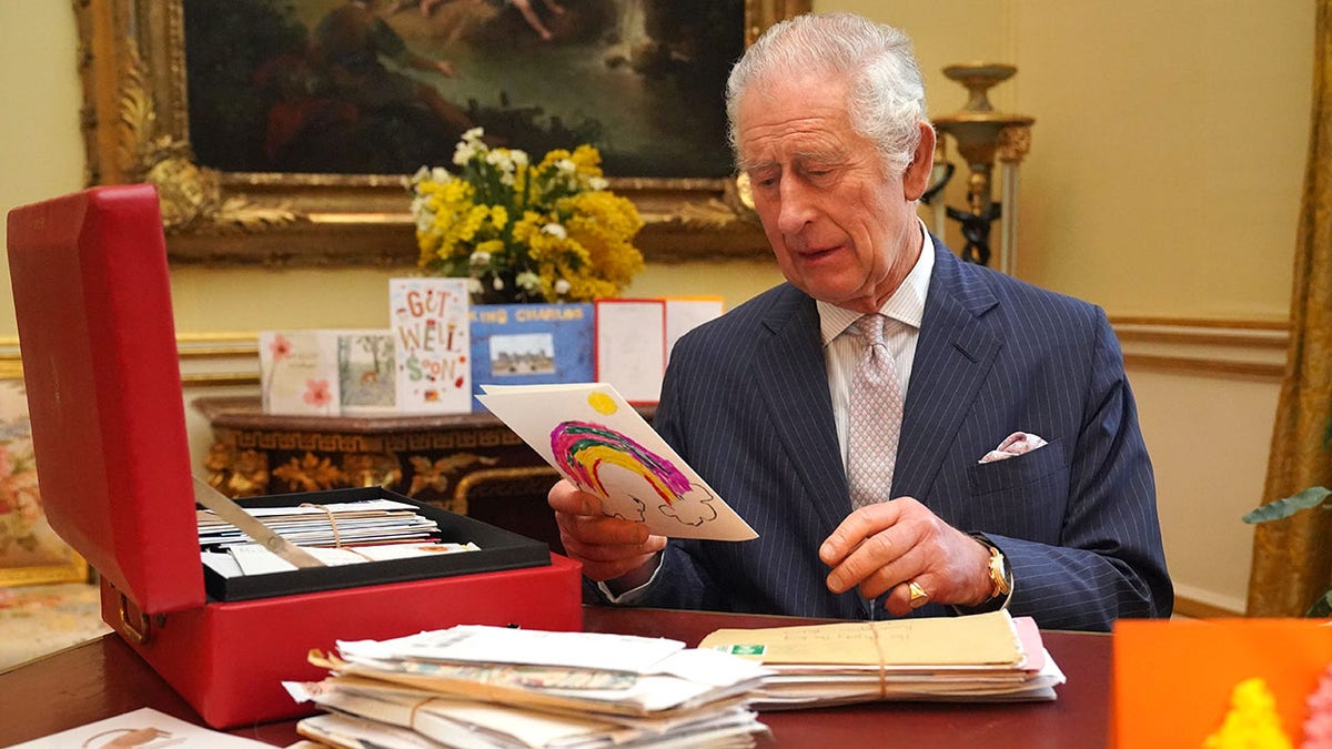 König Charles blickt auf eine farbige Karte, während er hinter seinem Schreibtisch sitzt