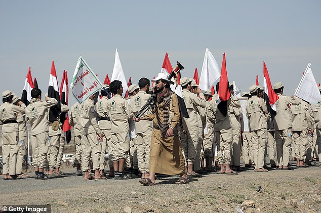 Scout team members carry Yemeni and Palestinian flags and placards depicting Yemen's Houthi leader Abdul Malek Bader AL-Den Al-Houthi and Houthi emblems at a rally in support of Palestinians in the Gaza Strip on February 4, 2024, on the outskirts of Sana'a, Yemen