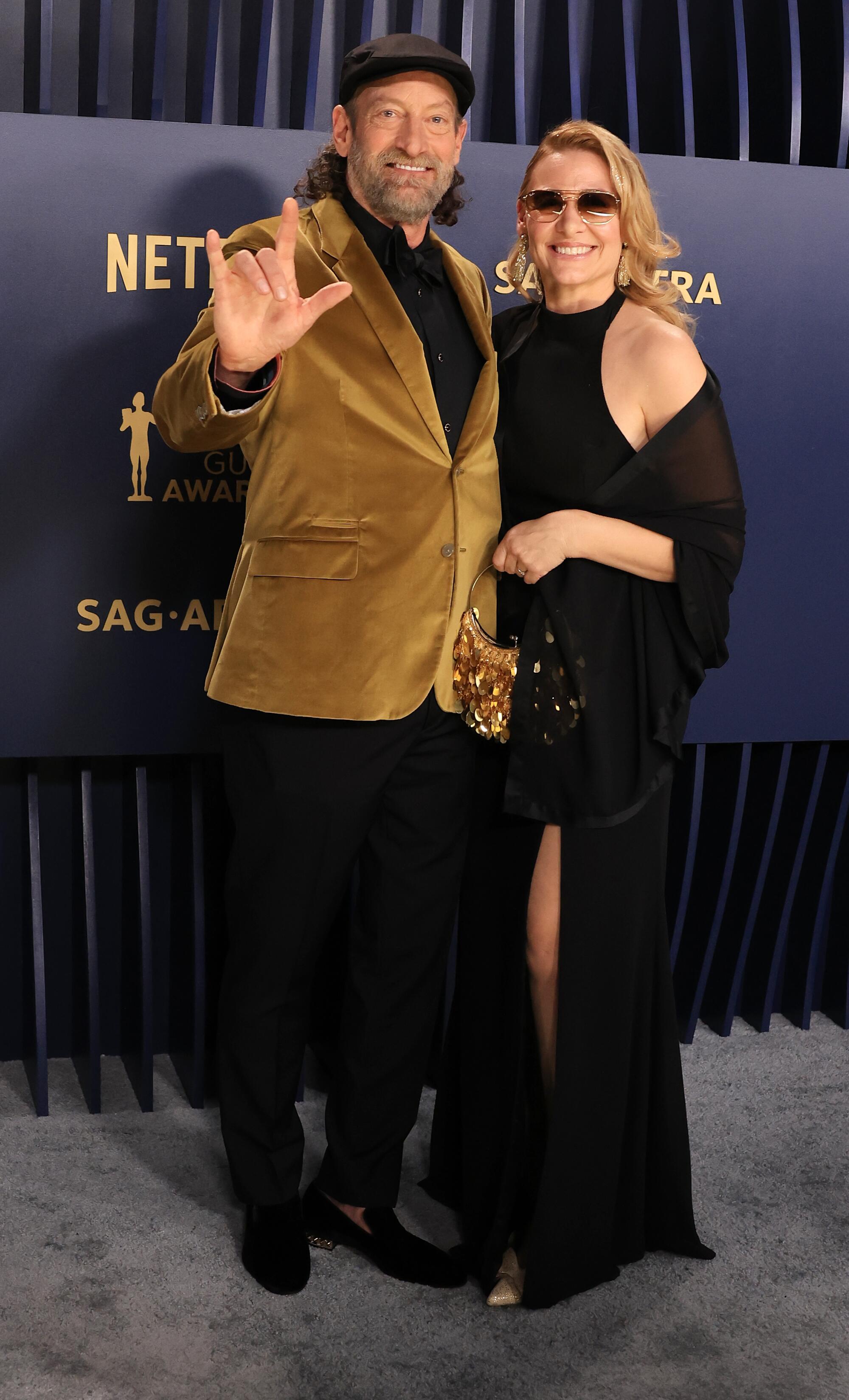 Troy Kotsur trägt bei den SAG Awards eine goldene Samtanzugjacke und Deanne Bray ein schwarzes Kleid.