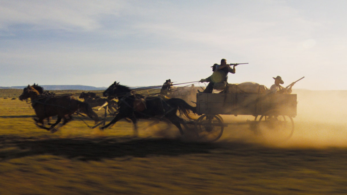 Cowboys schießen auf der Ladefläche eines Pferdewagens mit Waffen
