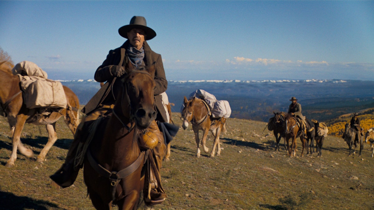 Kevin Costner trägt einen Cowboyhut, während er im Horizon-Trailer auf einem Pferd reitet