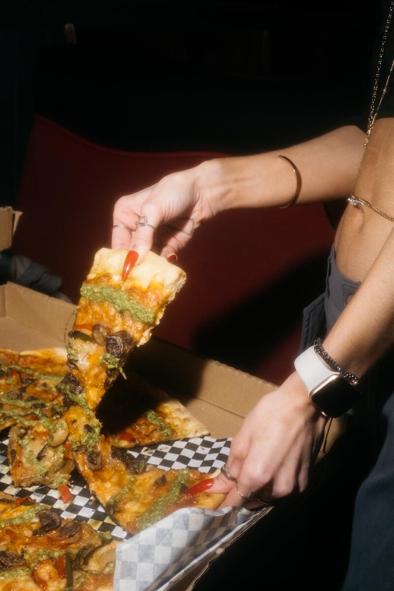 Eine Frau gönnt sich ein Stück Pizza.