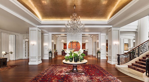 Die mit Kronleuchtern geschmückte Lobby des Hotels ist „mit Kunstwerken und riesigen Blumenvasen gesäumt“.