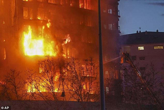 Feuerwehrleute arbeiten daran, die Flammen zu löschen, während sie weiterhin über den Wohnblock fegen
