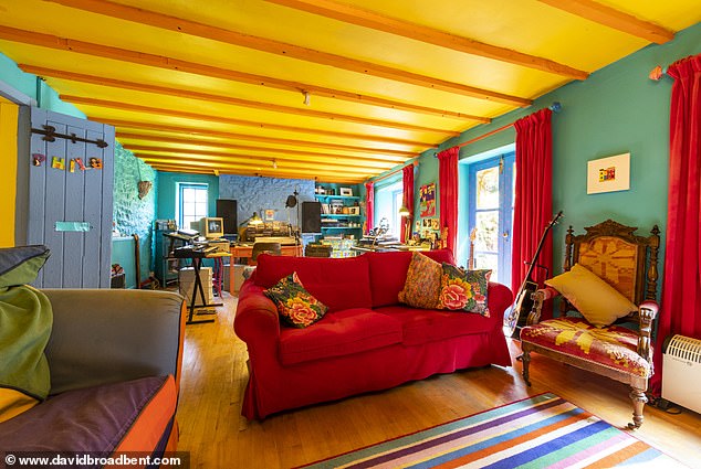 Das Wohnzimmer des Paares verfügt über leuchtend blaue Wände und eine gelbe Decke sowie einige farbenfrohe Möbel