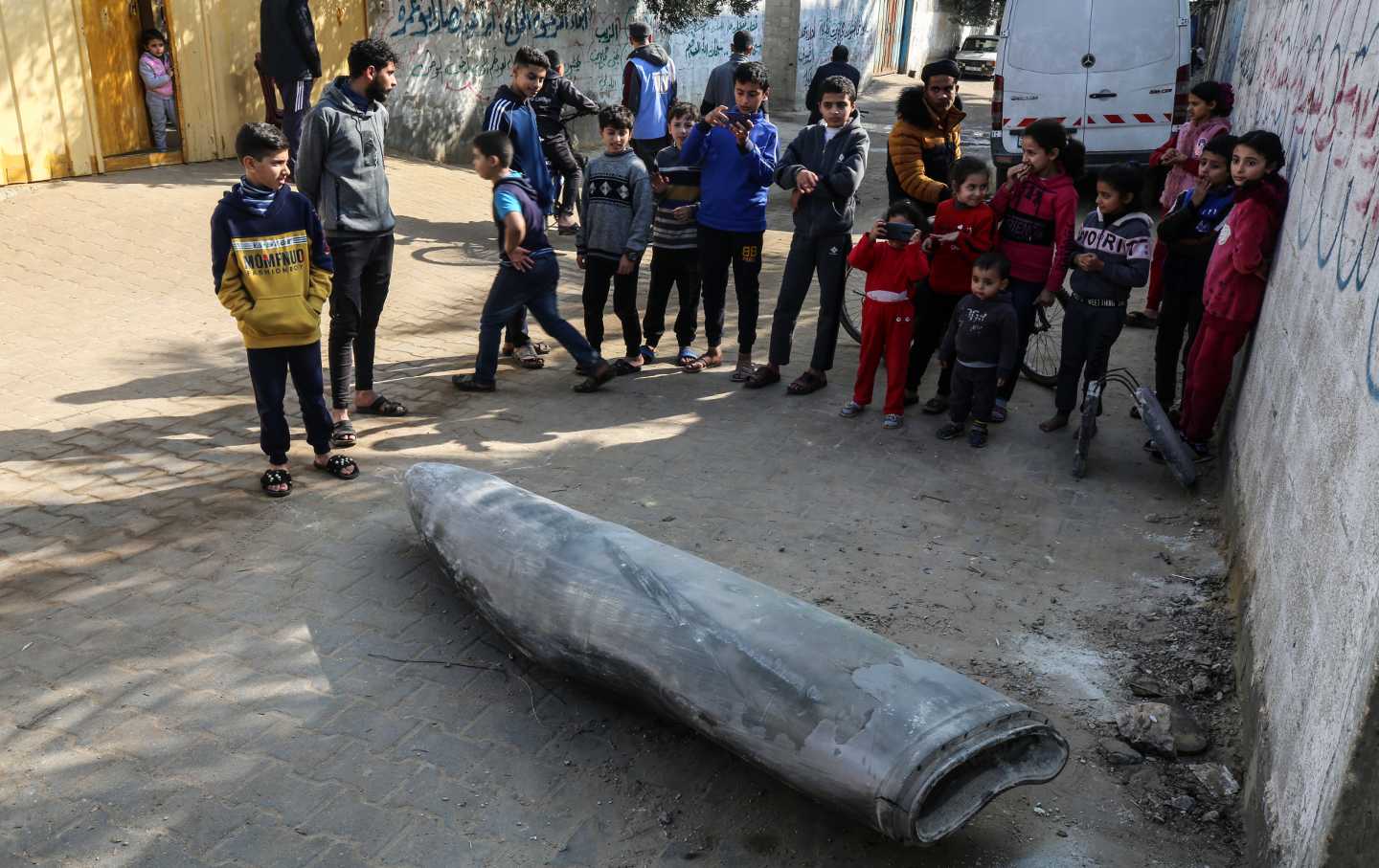 Palestinians are standing next to an unexploded bomb dropped by an Israeli F-16 warplane in Deir al-Balah, central Gaza Strip, on January 1, 2024