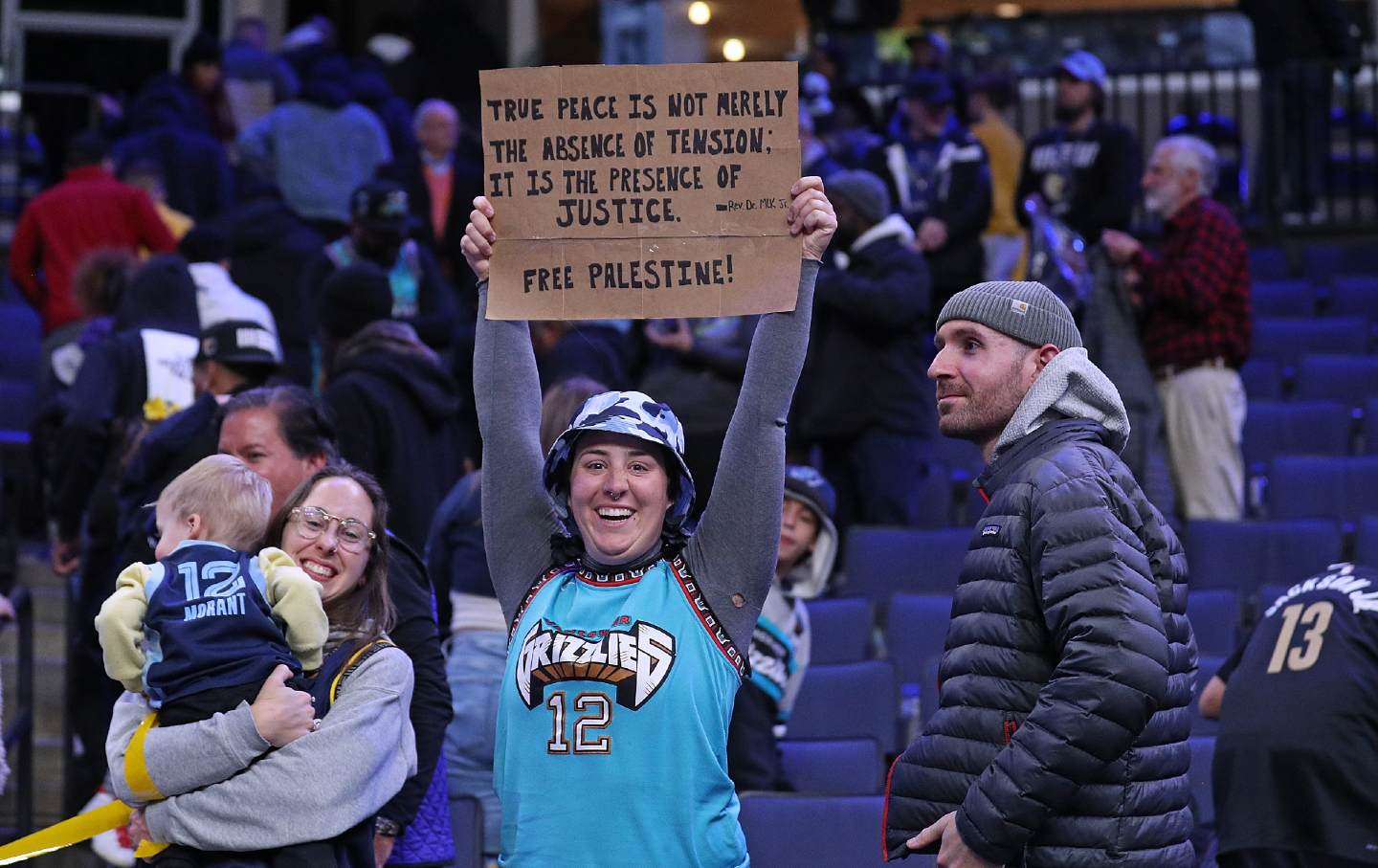 Frau im Grizzlies-Trikot hält bei einem Basketballspiel ein Pro-Palästina-Schild hoch