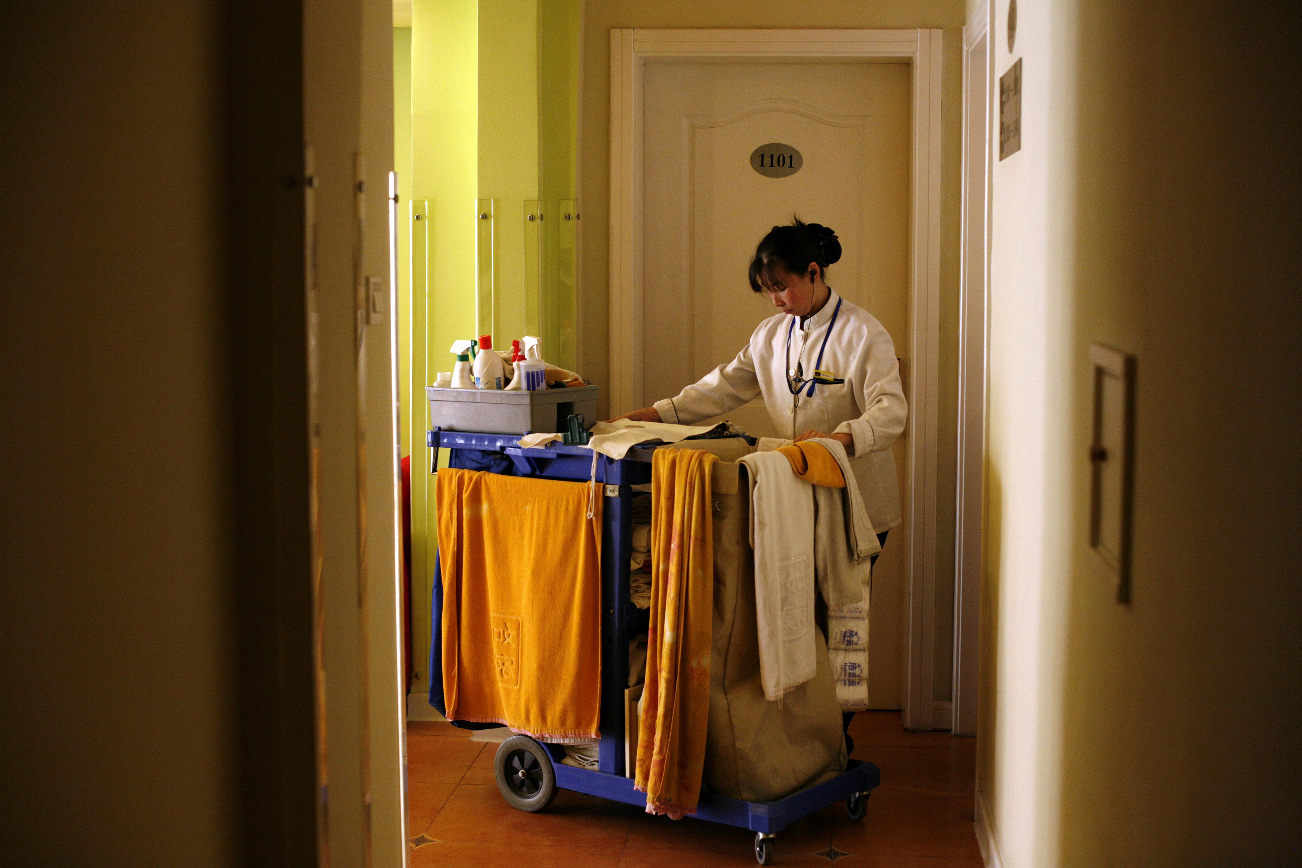 Ein Hotelmädchen betritt ein Zimmer mit einem Wagen voller Reinigungsmittel.