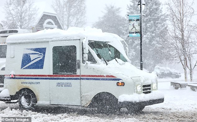 A mail truck drives as snow falls north of Lake Tahoe in the Sierra Nevada mountains during a powerful winter storm