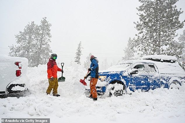 Men remove snow around their vehicles as snow blanketed Emerald Bay Road in Lake Tahoe, California, on Friday as the blizzard hit California's Sierra Nevadas