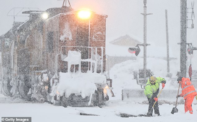 Workers clear train tracks as snow falls north of Lake Tahoe in the Sierra Nevada mountains during a powerful winter storm