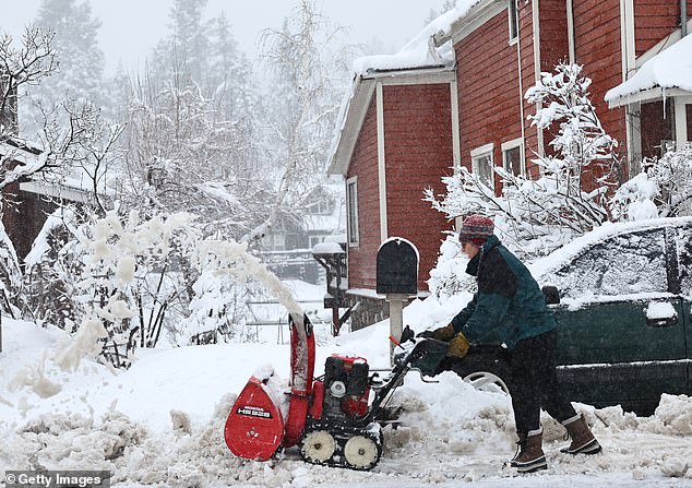 A resident can be seen using a snowblower as snow falls north of Lake Tahoe