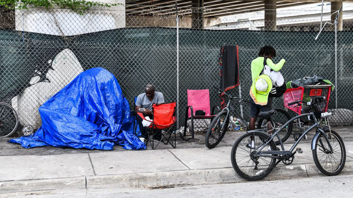 Ein Obdachloser sitzt neben seiner provisorischen Unterkunft auf einem Bürgersteig in Miami