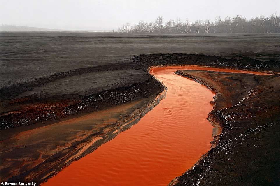 NICKEL TAILINGS, SUDBURY, ONTARIO, CANADA, 1996: This 'hellish picture' was taken outside the northern Ontario city of Sudbury in central Canada, which is famous for its nickel deposits. The book reveals that the image shows what looks like molten lava, but is in fact oxidized, water-borne waste, adding: 'It is actually an illusion of scale. We are not looking at a river, but at a small creek, just over a metre wide that can be easily jumped over'