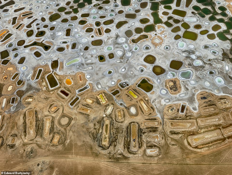 SALT PONDS, NEAR FATICK, ATLANTIC COAST, SENEGAL: This stunning picture shows a patchwork of hand-dug depressions, the result of artisanal salt harvesting. The colour variations are caused by salt-resistant microorganisms and varying rates of evaporation, the book explains