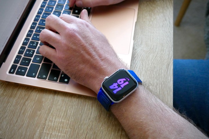 Mann trägt die Apple Watch SE 2 und tippt auf einem MacBook.
