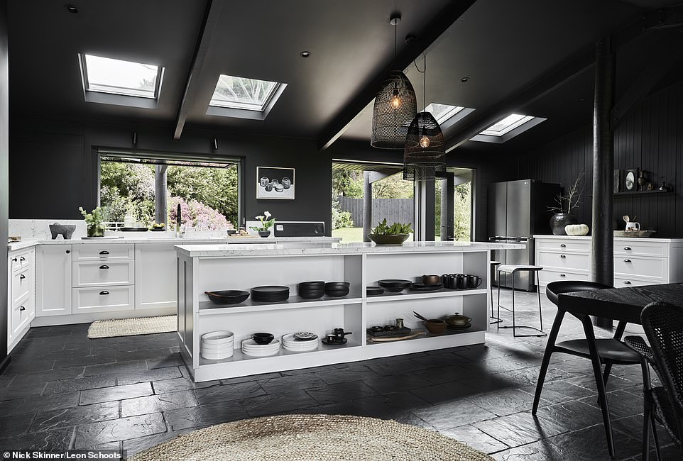 Weiß marmorierte Küchenbänke und Schränke setzen einen Kontrast zum Schwarz, während die holzgetäfelten Wände einen traditionellen Touch verleihen