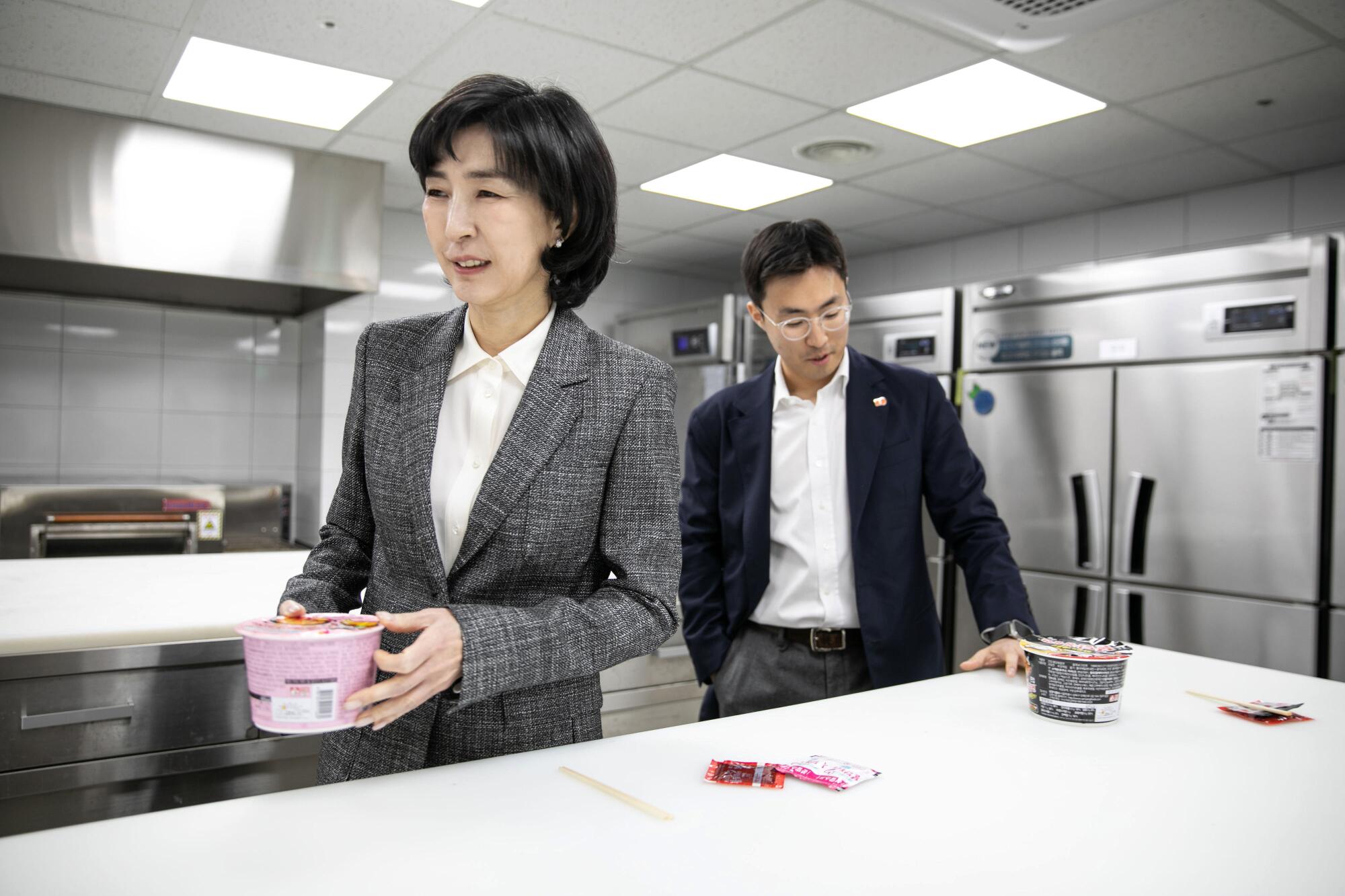   Kim Jung-soo, links, CEO und stellvertretende Vorsitzende, trägt die Tassennudeln zu einem Waschbecken 
