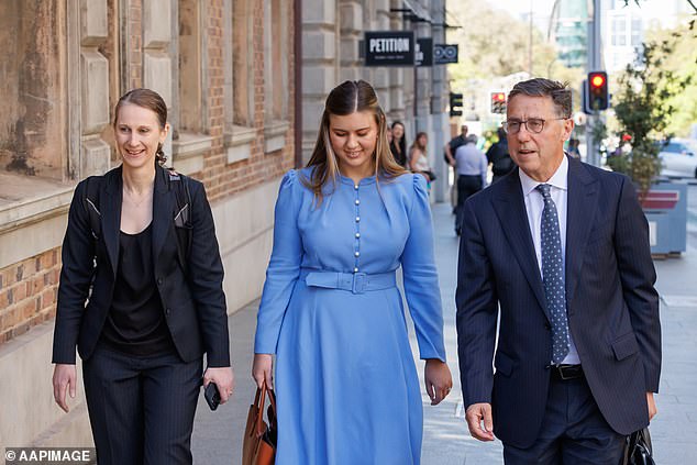 Brittany Higgins ist zu sehen, wie sie am Dienstagmorgen in einem kornblumenblauen Kleid zusammen mit ihrem Anwalt Leon Zwier das Gericht betritt