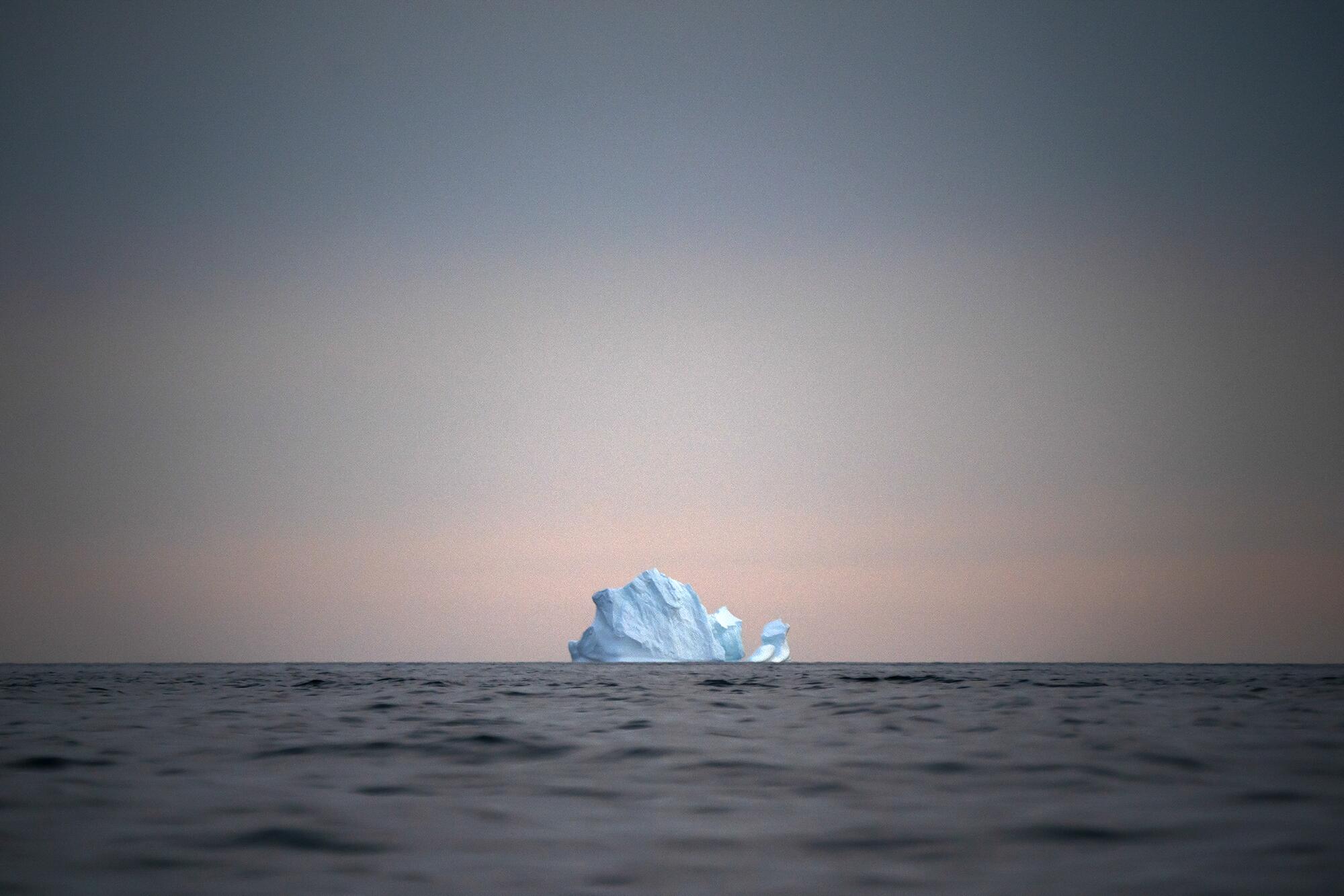Die Sonne geht auf einem großen schwimmenden Eisberg unter.